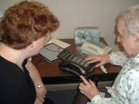 Female vision rehabilitation therapist teaching phone use with older woman