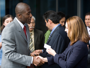 picture of African American man shaking Caucasian woman’s hand with background of culturally diverse individuals