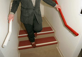 Picture of women’s feet and legs on steps marked with contrasting tape and the banister color contrasts to the wall