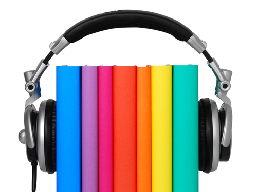 A neatly-stacked group of books set between a pair of headphones.