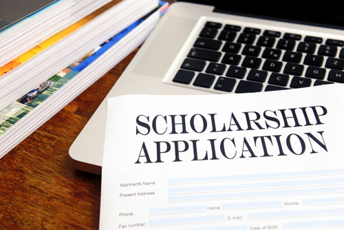 Blank scholarship application on desktop with books and laptop. 