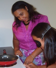 Lachelle teaching stovetop safety to a student wearing a low vision simulator