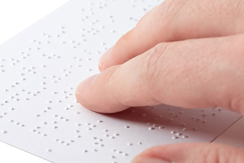 Close up of male hand reading braille text.