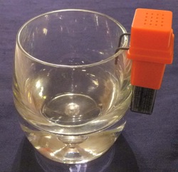 The prongs of an electronic liquid level indicator are placed over the rim of a clear old-fashioned glass