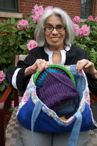 Charlotte Shrier seated outside, showing off the contents of her knitting bag