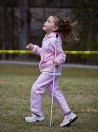 the author's daughter, gleefully running across a field with her white cane