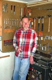 Gil Johnson standing by his tools and equipment in his workshop.