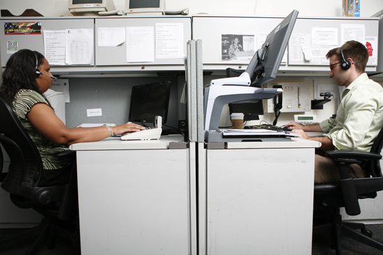 Two employees who are visually impaired, hard at work at their desks.