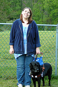 Rebecca Knaub, standing outside with her guide dog