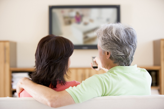 Couple watching television using remote control.