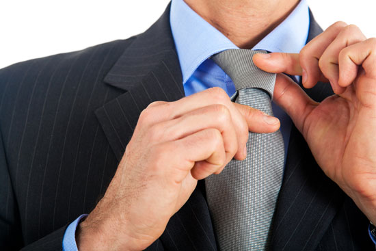 Man in business suit adjusting his tie.