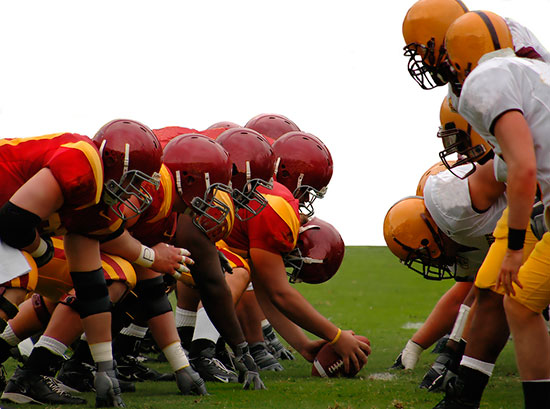 The front line of a group of football players, competing.