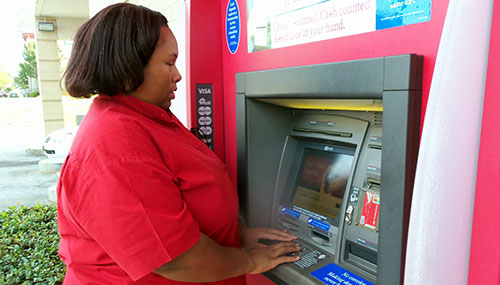 the author standing at an ATM, hands on the keypad