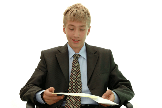 A teenager in a suit and tie reads his notes, preparing for a job interview