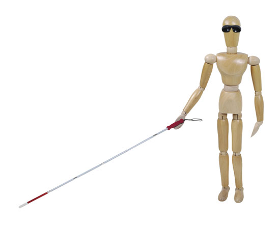 A wooden figure wearing sunglass and using a long white cane.