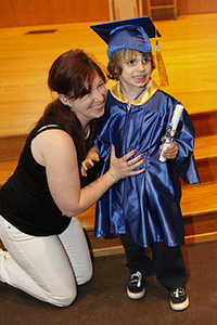 mother kneeling with her daughter, who is visually impaired, at a grade school graduation ceremony