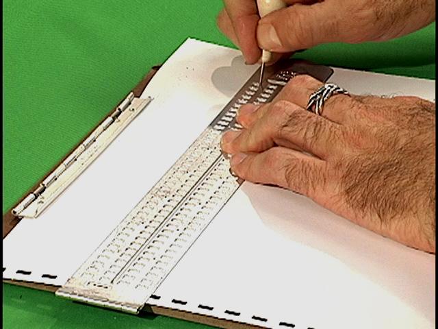 Photo of person using a 4-line slate and stylus.