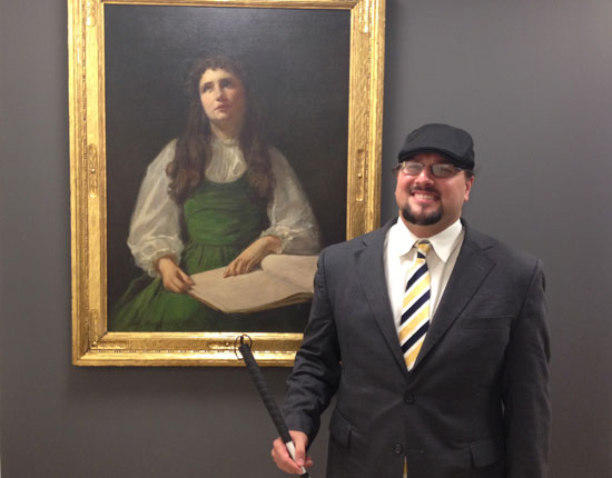 Joe Strechay poses in front of a Helen Keller painting in AFB's New York Office.