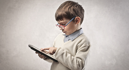 boy wearing glasses touching an iPad