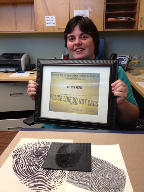Alexis Read sitting at desk holding a framed certificate