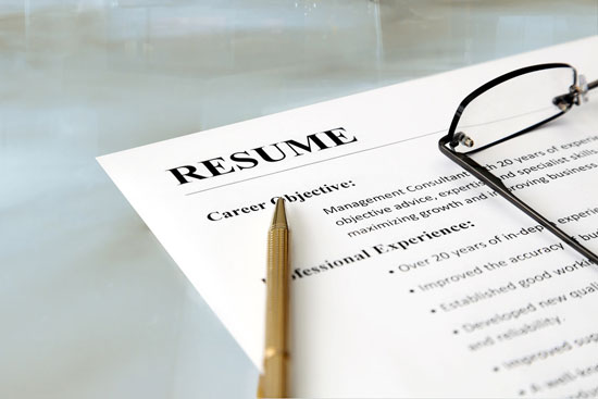 Close-up of a resume with pen and glasses on the table.