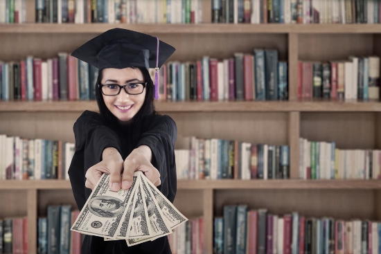 Young female graduate holding money at library.