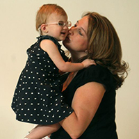 Mother kissing her daughter, who is wearing glasses