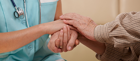 Closeup of joined hands of nurse and elderly patient