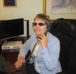 Janice Cantrell smiling while sitting at her desk on the phone