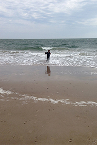 Myat enjoying the waves at Coney Island, white cane in hand