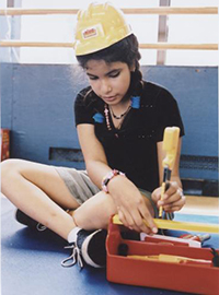 girl playing with plastic tools, wearing construction hat