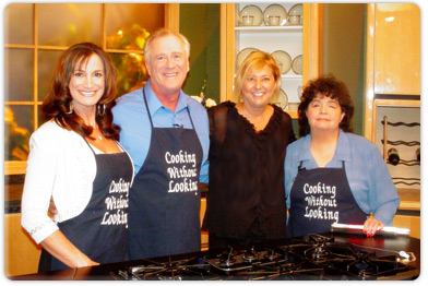 Image of four people standing behind a stove on the set of the program Cooking Without Looking.