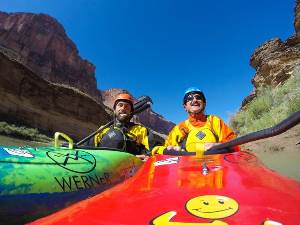 Erik W. sitting in a kayak next to his guide in another kayak in a river below a canyon