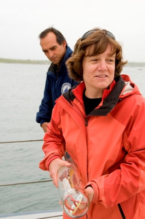 Amy Bower aboard a ship holding a drifting buoy with husband, David