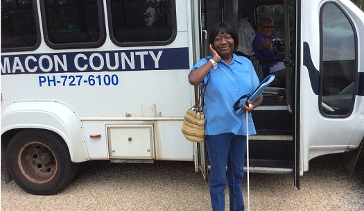 Macon County support group member standing outside bus holding cane