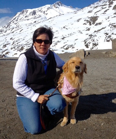 Audrey and dog guide Sophie in Alaska with snow covered mountain in background