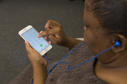 Woman using an iPhone with earbuds connected.