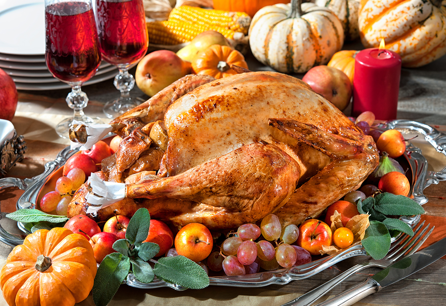 Thanksgiving dinner. Roasted turkey on holiday table with pumpkins, candles, and fruit