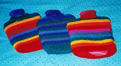 three knitted hot water bottle covers in bright colors