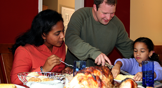 a mother, father, and daughter having Thanksgiving dinner at homer