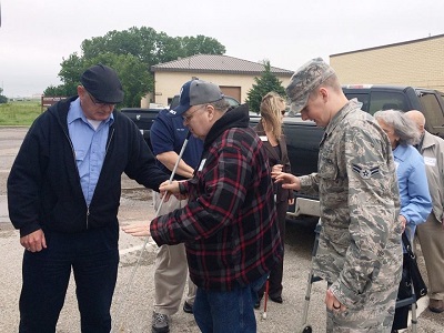 older veteran with cane helped by younger veteran