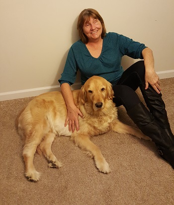 woman seated on floor with arm around dog guide