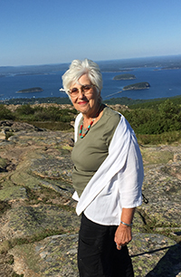 Judith Millman, smiling in a beautiful coastal setting