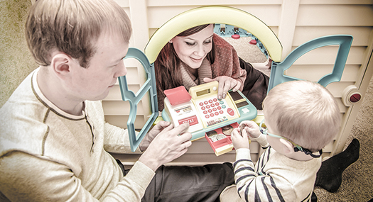 Parents play with their child and a pretend cash register