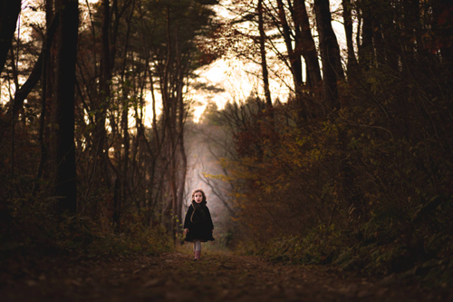 small child in a wooded area at dusk 