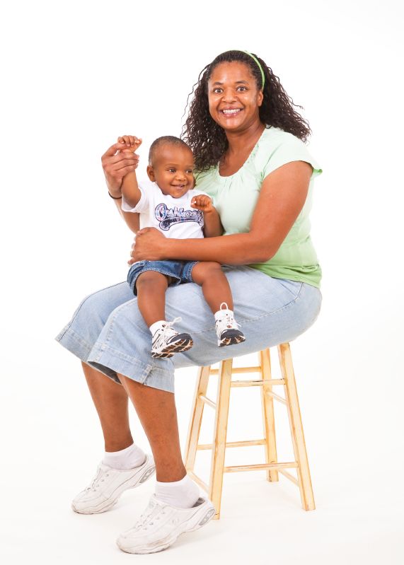 mom with son on her lap - both are smiling widely, and the mom is holding her child's hand up high