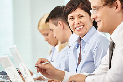 Happy female employee sitting at a conference table with coworkers