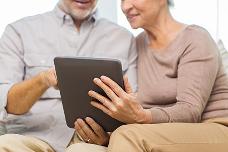 Man and woman sitting together looking at a tablet 