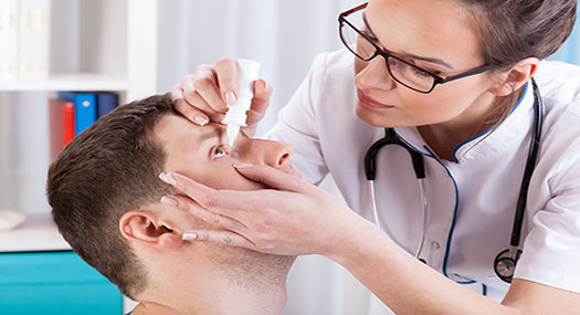 A doctor helps a patient apply eye drops 