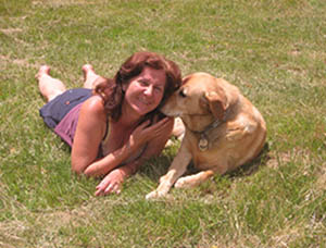 Maribel laying in the grass with her guide dog Nev